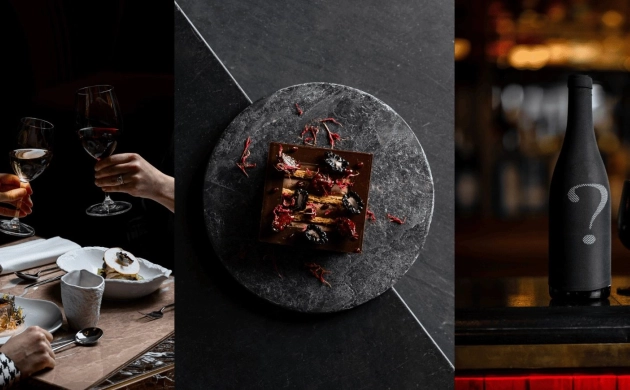 Gourmet dining experience with wine toasts, a refined dessert on a dark slate, and a mystery wine bottle with black glasses