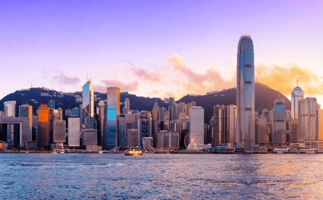 Panoramic view of Hong Kong’s skyline at sunset, with illuminated skyscrapers and mountains in the background