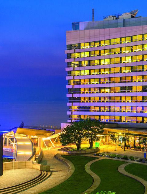 Night view of Le Méridien Hong Kong, Cyberport, with illuminated windows, modern architecture, and a landscaped garden overlooking the sea